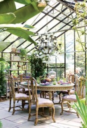 a bright vintage sunroom with refined wooden furniture, an oversized chandelier and potted greenery, colorful textiles