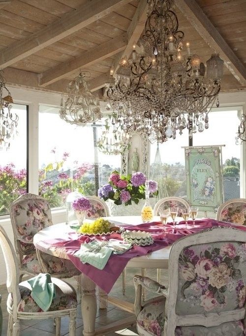 a luxurious vintage sunroom with windows all around, crystal chandeliers, refined furniture and floral chairsfloral artworks