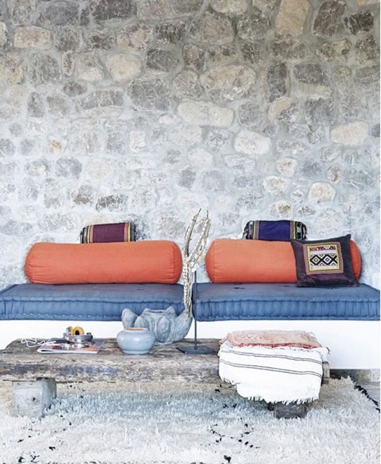 a bright Moroccan patio in navy and orange, with a low table on wheels and bright textiles