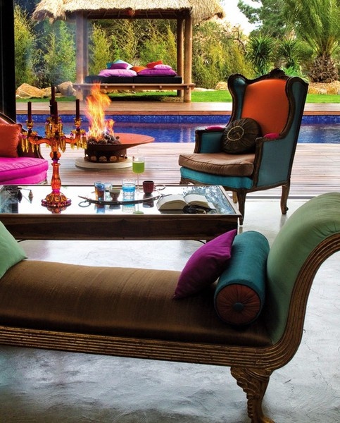 an elegant and colorful Moroccan meets luxurious patio with bright furniture and pillows, a fire pit and a candelabra