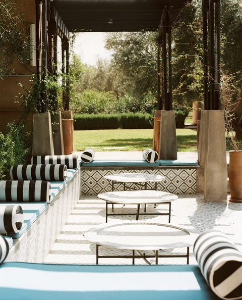 a black and white striped patio with touches of turquoise and low coffee tables