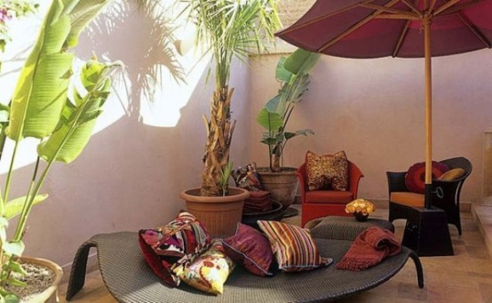 a neutral patio filled with contemporary wicker furniture, colorful pillows and potted plants for a Moroccan feel