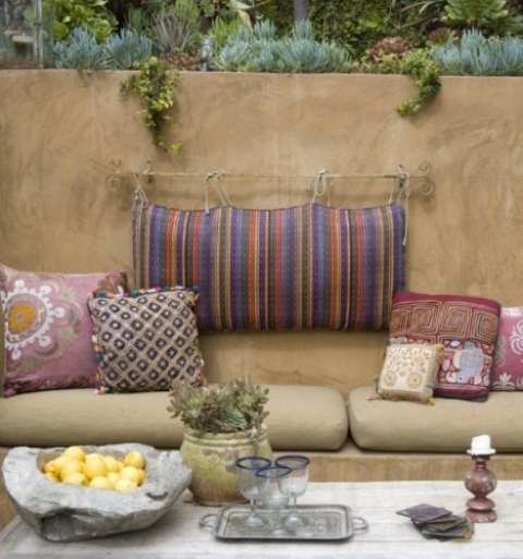 a simple Moroccan patio with colorful pillows, potted greenery and stone decor