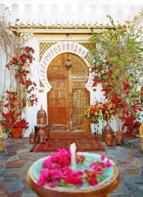 a colorful Moroccan space with lots of rugs, Moroccan lanterns and a fountain with petals