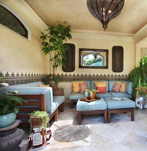 mosaic tiles on the walls, blue upholstered furniture, Moroccan lanterns and potted greenery