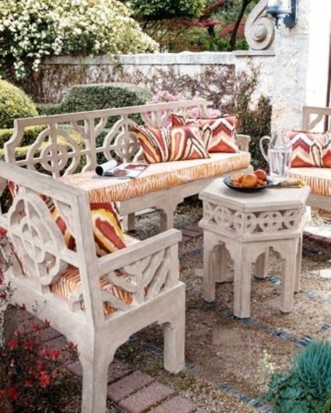 a cozy Moroccan patio with white carved furniture and bright textiles