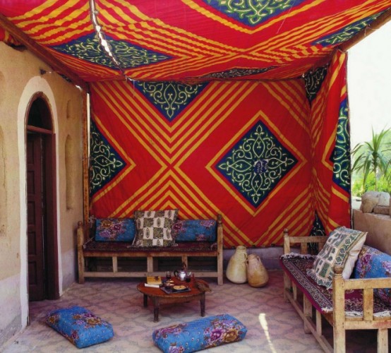 a bright Moroccan space done in blue and red, with patterns and comfy furniture