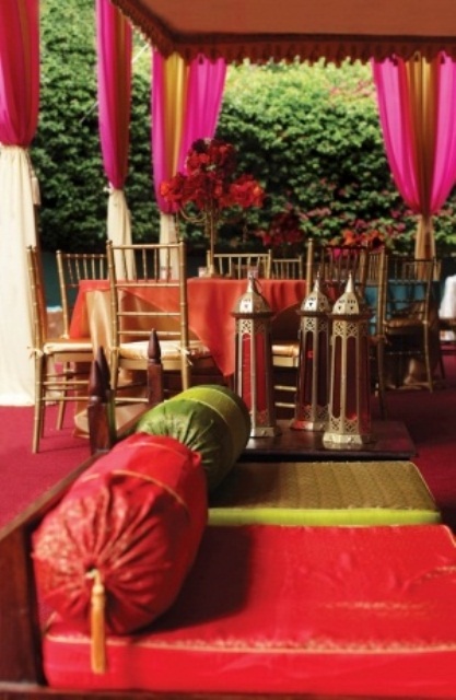 a pink, red and green Moroccan patio with lanterns, bright pillows and curtains