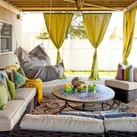 a colorful Moroccan patio with neon yellow curtains, a mosaic tile table and wicker furniture