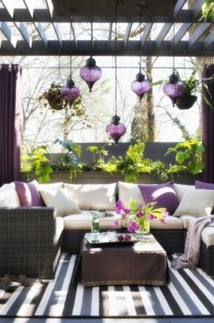 a chic terrace done in dark shades and white and with purple Moroccan lanterns over it
