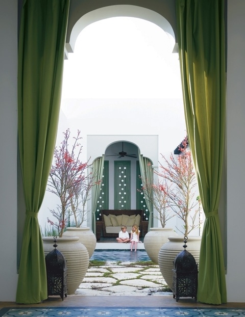 a Moroccan space with grene curtains, Moroccan lanterns and potted trees 