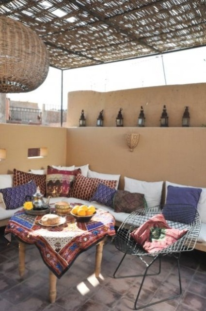 sandy walls, colorful textiles with bright patterns, Moroccan lamps and a wicker lampshade