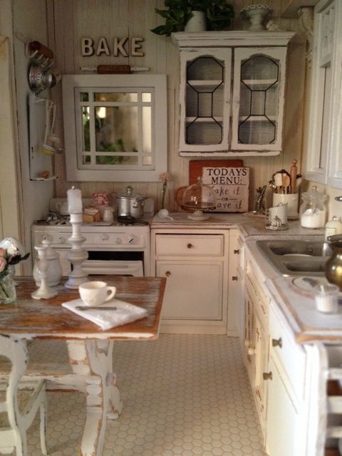 a rustic shabby chic kitchen in neutrals, with wooden walls and vintage cabinets, a shabby chic table and kitchen island and shabby chairs