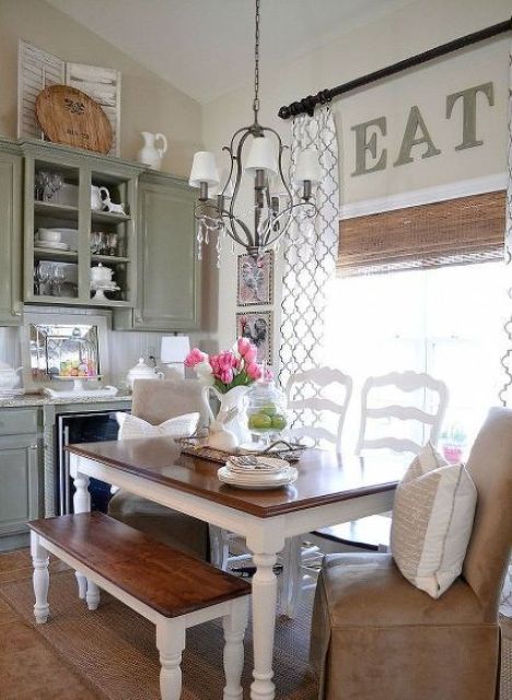 a vintage kitchen in olive green, white dining set with stained surfaces, a vintage chandelier and a leather chair