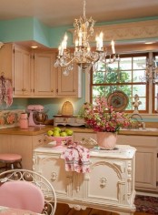 a delicate shabby chic kitchen with pastel green walls, white vintage furniture, a vintage chandelier, pastel pink touches and floral linens
