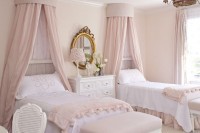 a delicate princess-style blush shared bedroom with vintage beds with blush canopies and bedding, poufs, a desk and a chair is just gorgeous