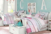 a pastel shared girls’ bedroom with a turquoise accent wall, white vintage furniture, white chests for storage and nightstands, floral printed bedding and pillows