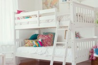 a stylish white shared girls’ bedroom with a bunk bed, colorful pillows, white stools, a hot pink printed rug, colorful toys, decor and details