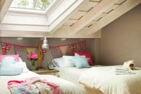 a relaxed attic shared girls’ bedroom with beds, vintage bedding and a nightstand, pink stools and a bright fabric banner is very cool and fresh