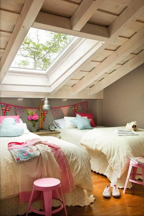 a relaxed attic shared girls' bedroom with beds, vintage bedding and a nightstand, pink stools and a bright fabric banner is very cool and fresh