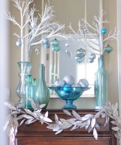 beautiful blue, turquoise and silver Christmas decor with vases, white branches, blue and white ornaments and a garland of silver leaves