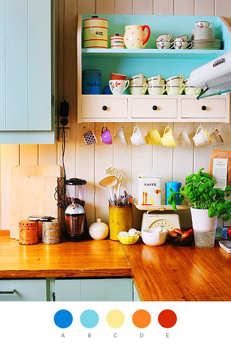 a colorful kitchen with blue cabinets, wooden countertops and bold mugs and plates for a funny touch