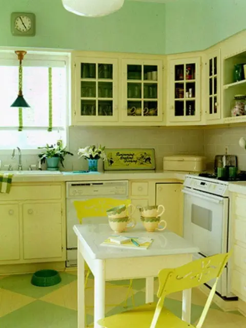 a retro kitchen with grene walls, light yellow cabinets, a white table and yellow chairs is a cool and welcoming space
