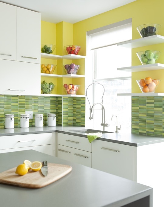 a stylish contemporary kitchen with yellow walls, green mosaic tiles, white cabinets and grey countertops rocks