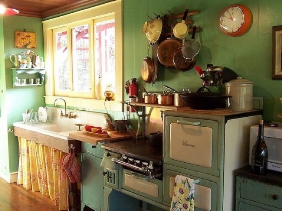 a vintage kitchen with green walls, cabinets and a bright yellow curtain under the sink