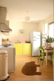 a neutral retro kitchen with a bright yellow cabinet, a mint fridge and a bold green chair and some succulents on the windowsill