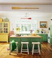 a bright farmhouse kitchen with white walls and a ceiling, green cabinets, a bright yellow buffet, colorful blooms