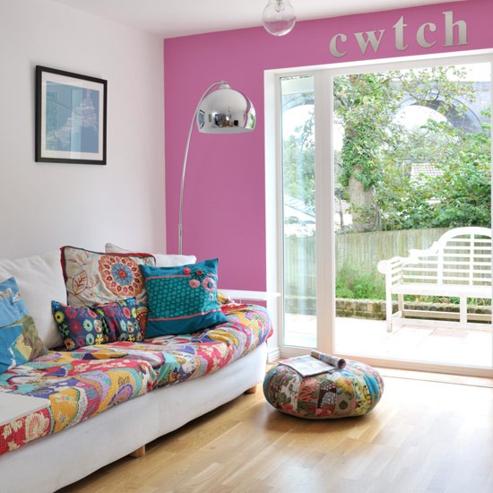 A hot pink wall, bright printed pillows and upholstery make the living room feel and look bright and summer like