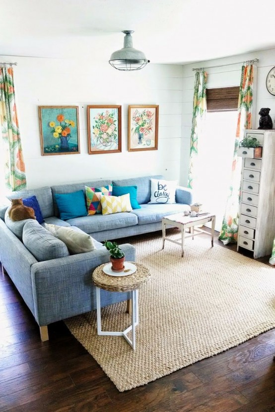 a neutral living room with a blue sofa, colorful pillows, bright printed curtains and a gallery wall for a summer feel