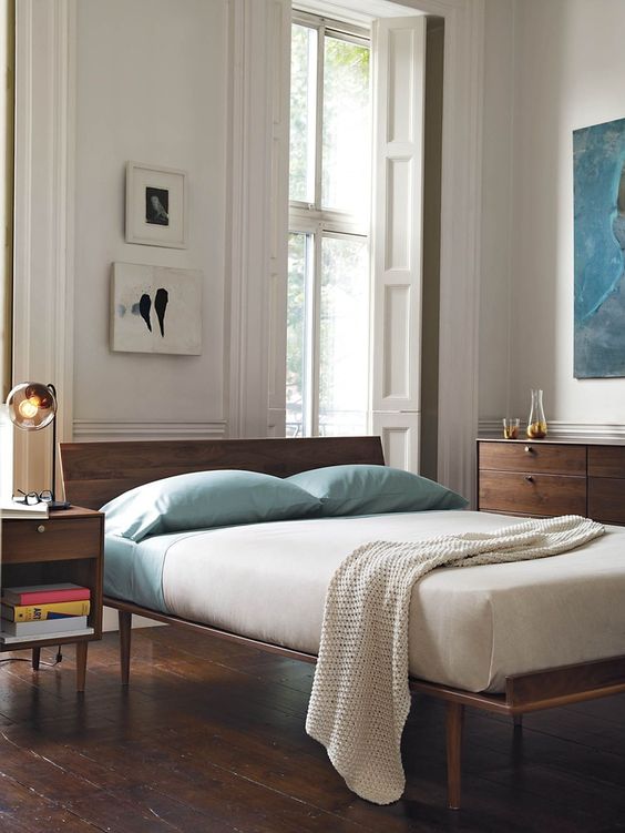 A mid century modern bedroom with elegant rich stained wooden furniture, artworks and some aqua accents