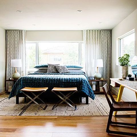 A stylish mid century modern bedroom with a large bed, nighstands, desks and chairs plus much light