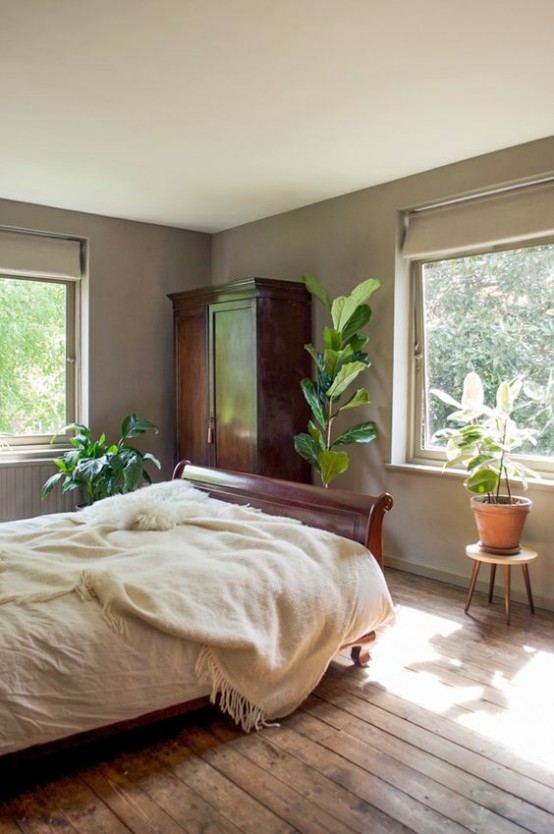 a mid-century modern meets boho bedroom with rich stained furniture, potted plants and shades