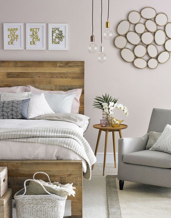 A welcoming mid century modern bedroom with a pallet wood bed, cozy furniture, artworks and hanging bulbs