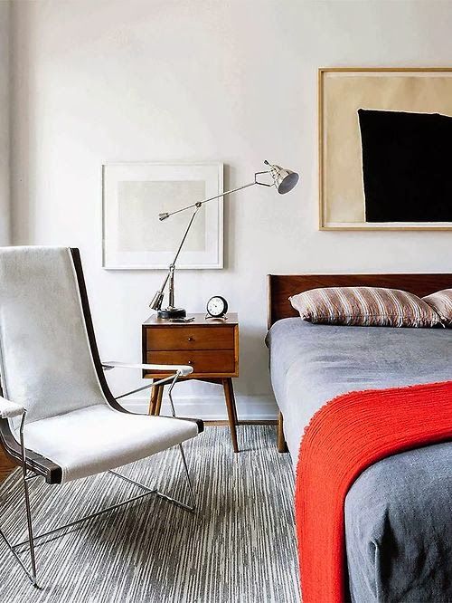A laconic mid century modern bedroom with a catchy thin chair, a cozy bed, a mid century nightstand and a lamp