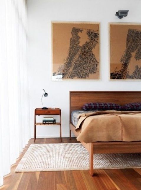 A chic mid century modern bedroom with rich stained furniture, artworks, a rug and moody bedding