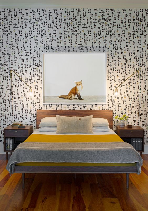 A catchy mid century modern bedroom with geometric wallpaper, simple stained furniture and gilded table lamps