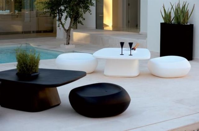 An ultra minimalist outdoor space with minimal black and white low coffee tables and stools is a bold and catchy space