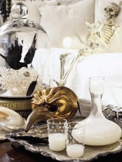 glam Halloween styling – candles in pearled candleholders, a gold mask, bats and a skeleton is a chic idea