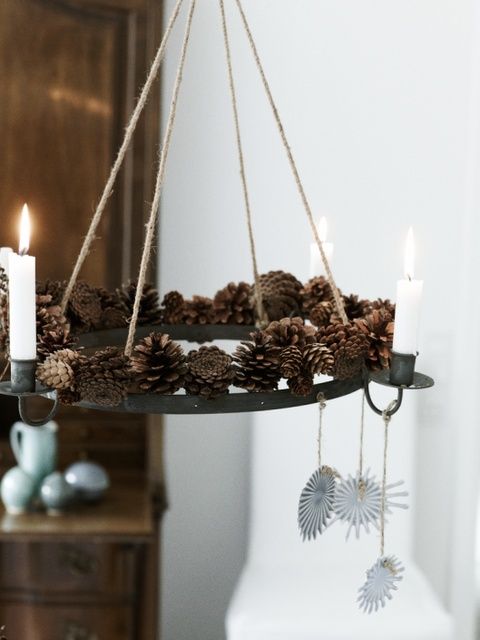 a creative pendant chandelier with pinecones and candles plus some paper decorations hanging down for a natural feel