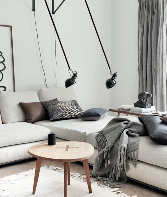 a neutral Scandinavian living room with touches of black for drama and cozy blankets and pillows
