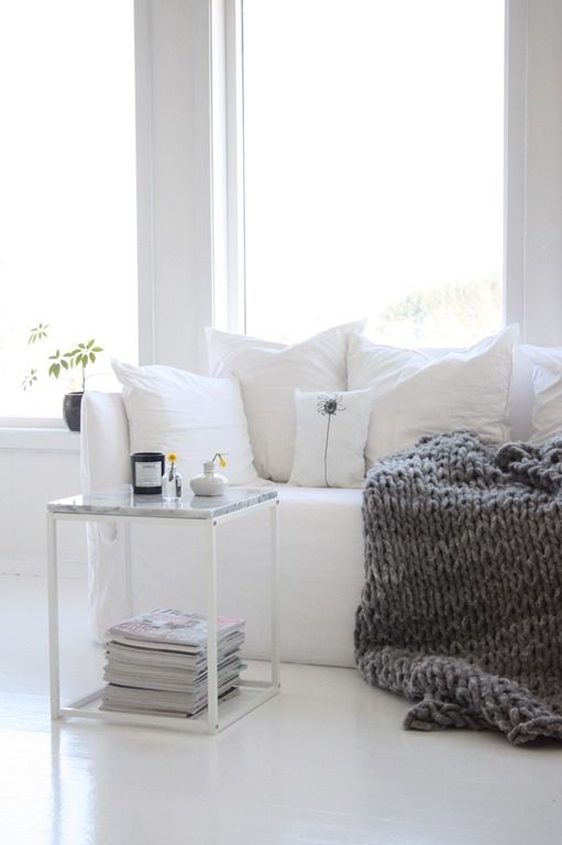 A cozy white nook spruced up with a heavy knit blanket for the fall is a great Nordic inspired idea