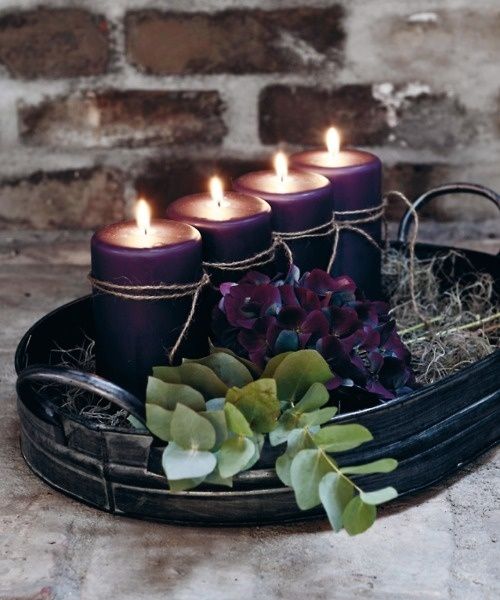 a fall Scandinavian centerpiece of a dark metal tray, purple candles, hay and purple hydrangeas and eucalyptus