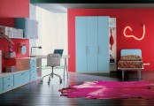 a cool teen bedroom with red walls, blue furniture, a neon sign, a brigth rug and bold printed bedding is super cool