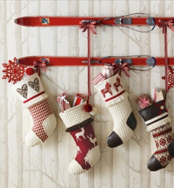 vintage red skis used as holders for black, red and white stockings that holid various gifts can become a nice outdoor or indoor decoration for a vintage-inspired space