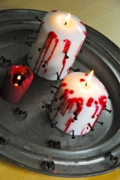 basic pillar candles decorated with black nails and red wax look bold and very Halloween-appropriate