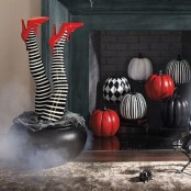 black, white and red patterned pumpkins and matching witches’ legs in a cauldron are amazing for Halloween decor